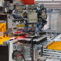 Die Stacking-Anlage der Referenzfabrik.H2: Hubeinheit für Stapel (orange), Werkstückträger mit Führungen (Mitte), Transfersystem, Greifer mit Fließsauger, Abstreifer und zwei Kameras zur Lagekorrektur.